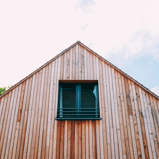 a-wooden-house-with-attic-window-under-cloud-studded-sky